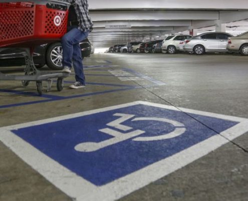 Image of undercover police officer standing next to disabled parking spot to monitor for "improper" use of disabled parking permits