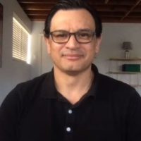 man in glasses and wearing dark shirt faces toward camera