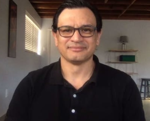 man in glasses and wearing dark shirt faces toward camera