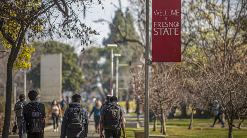 Students with backpacks walking outside at Fresno State campus