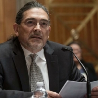 Census Bureau Director nominee Robert Santos wears glasses and a suit and sits at a podium on Capitol Hill.