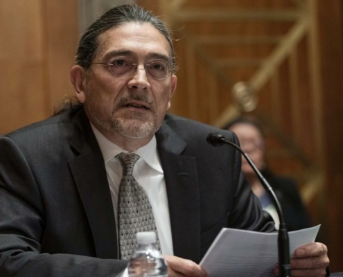 Census Bureau Director nominee Robert Santos wears glasses and a suit and sits at a podium on Capitol Hill.