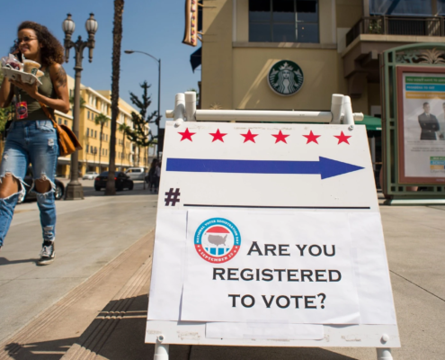 Sign with text "Are you registered to vote?" on sidewalk