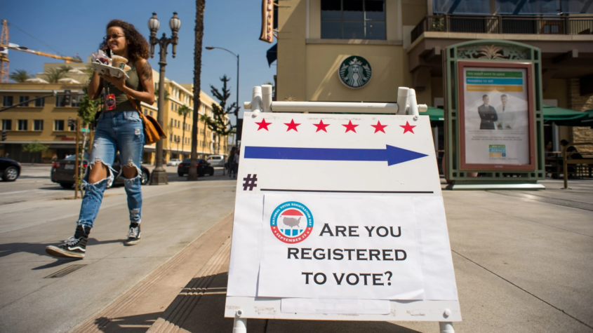 Sign with text "Are you registered to vote?" on sidewalk