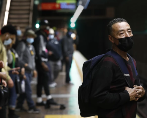 Man in a suit wearing a mask and carrying a backpack stands and waits for the Metro.