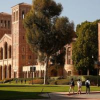 Three students walk across the parking lot on the UCLA campus in front of Royce Hall