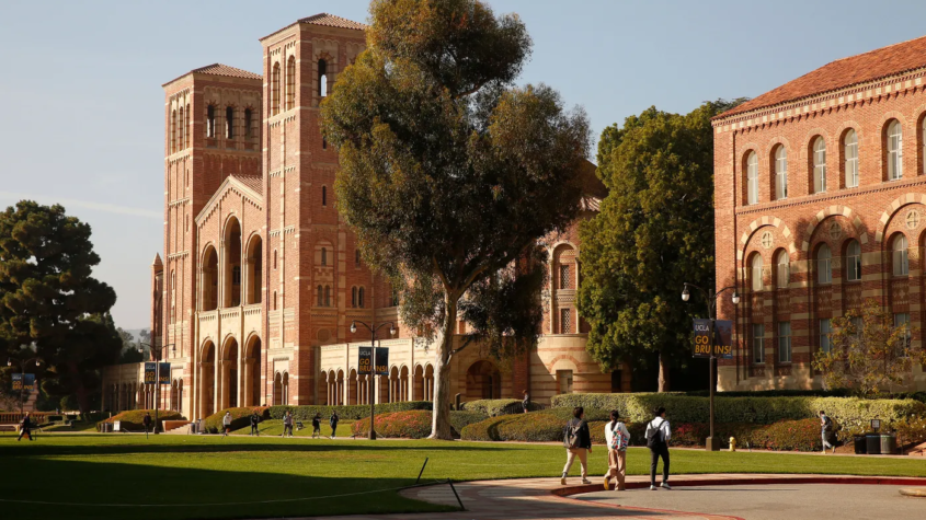 Three students walk across the parking lot on the UCLA campus in front of Royce Hall