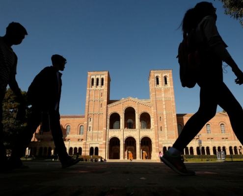 Silhouettes of students walk by in front of Royce Hall on UCLA campus.