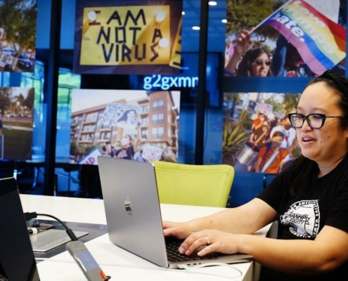 Woman at laptop computer in front of wall of poster