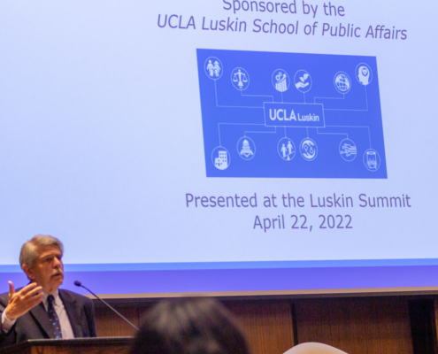 Zev Yaroslavsky gestures in front of project screen showing opening slide at Luskin Summit event