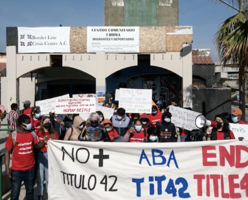 Protesters march with a banner that says "End Title 42"