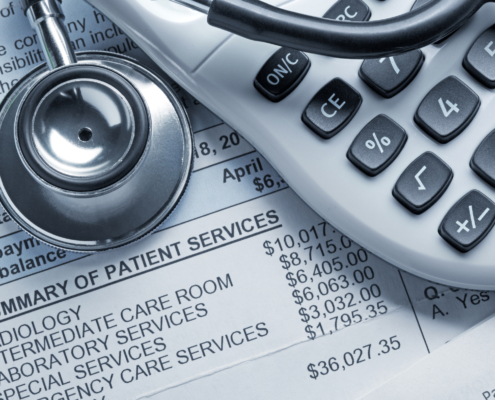 A stethoscope and a calculator rest on top of a medical bill.