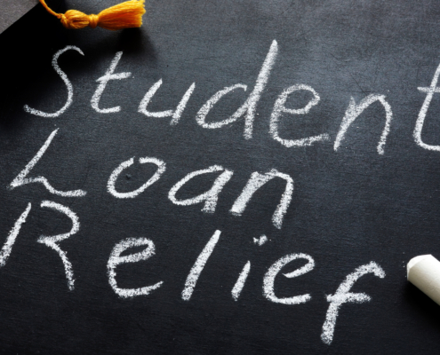 Student loan relief written on the blackboard and graduation cap.
