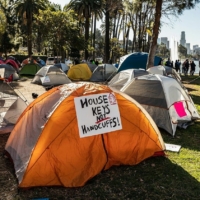 tents in park, with sign reading "House Keys Not Handcuffs"