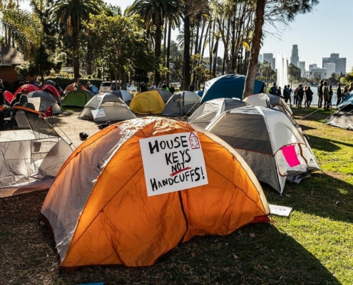 tents in park, with sign reading "House Keys Not Handcuffs"