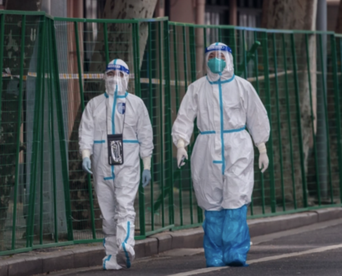 Two people walk side by side dressed in full PPE during the Omicron outbreak in China.