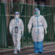Two people walk side by side dressed in full PPE during the Omicron outbreak in China.