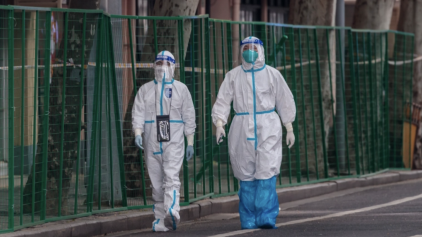 Two people walk side by side dressed in full PPE during the Omicron outbreak in China.