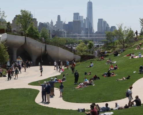 People sitting on the grass and strolling around Little Island Park in Manhattan on a sunny day.