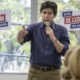 Mayoral candidate Kevin de León stands in front of his campaign staff while pointing and speaking into a microphone