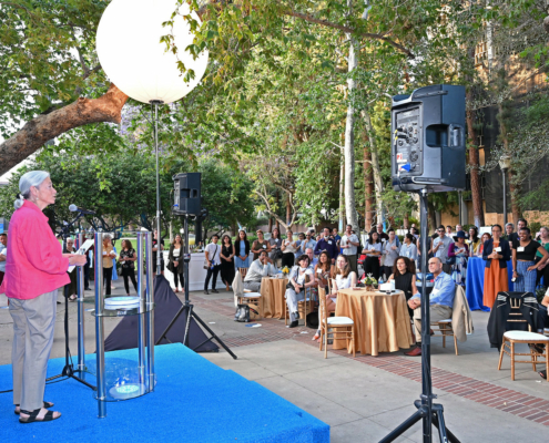 people gather outdoors to watch speaker at reunion event