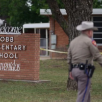 sheriff in front of brick elementary school sign