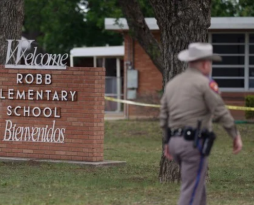 sheriff in front of brick elementary school sign