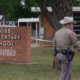 sheriff in front of brick elementary school sign