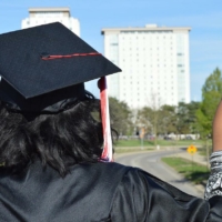 back of person wearing can and gown, outdoors
