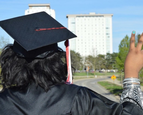 back of person wearing can and gown, outdoors