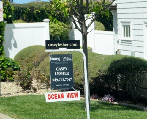 For sale sign in a yard in front of a house
