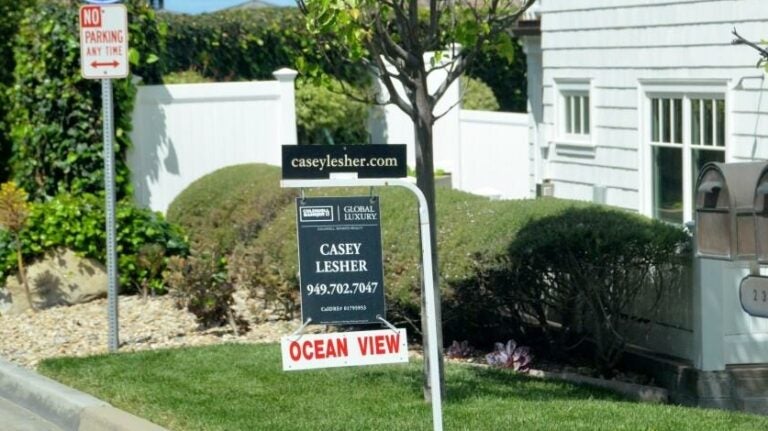 For sale sign in a yard in front of a house