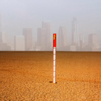 Thermometer in the desert with city buildings in the background