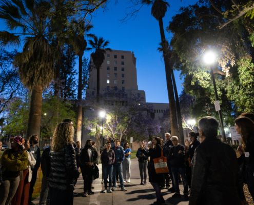 park lighting glows in the background as a group of people gather in an urban park in Los Angeles