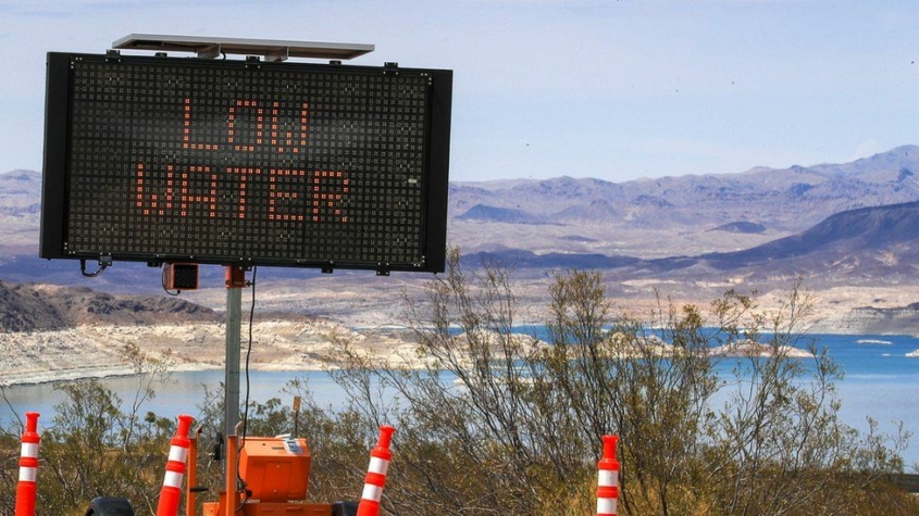 A road sign reads "Low Water" overlooking a lake.