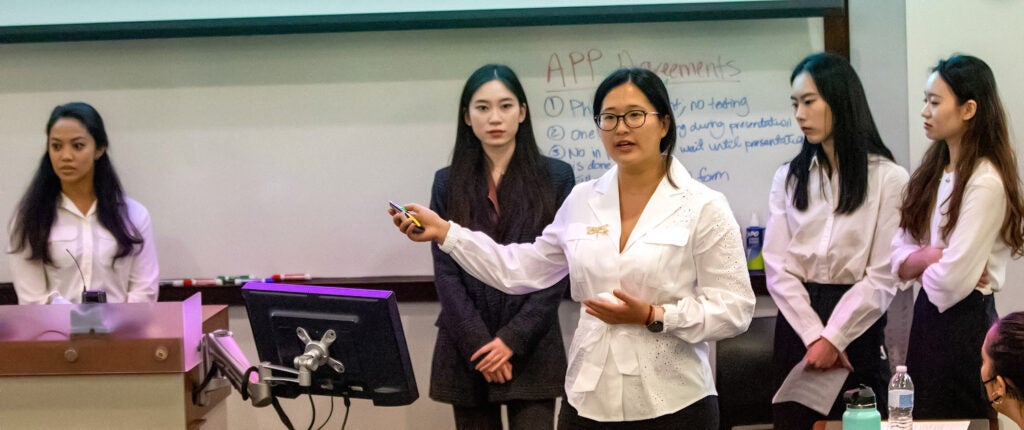 five young women in front of an erasable board in a classroom
