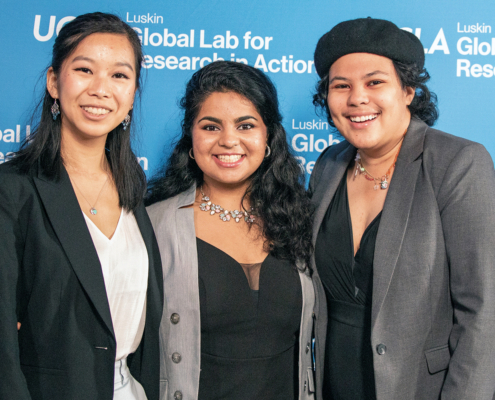 three young people smile in front of UCLA backdrop