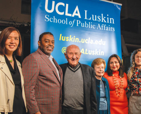 group of people pose in front of UCLA backdrop
