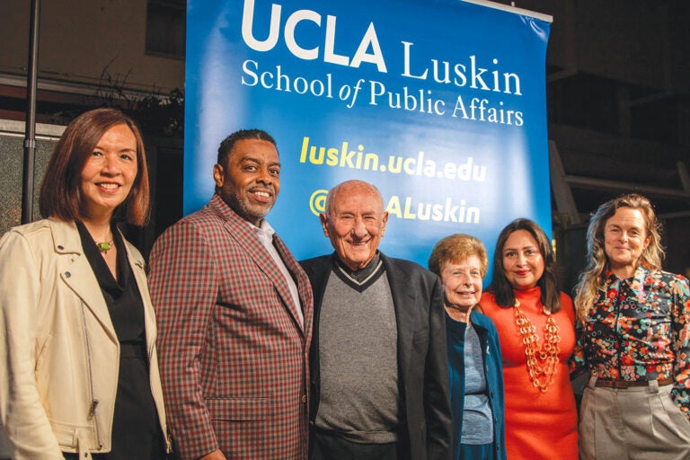 group of people pose in front of UCLA backdrop