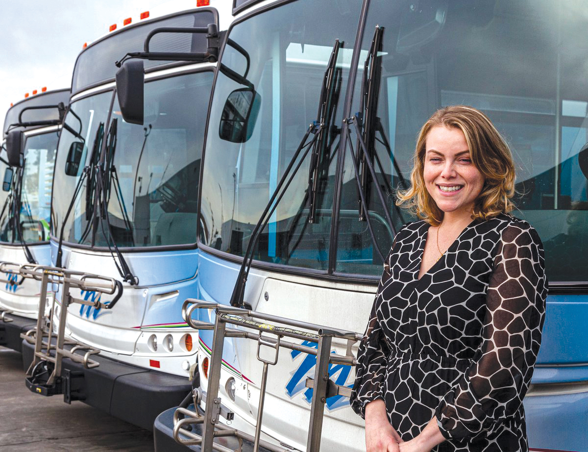 woman poses with buses in background