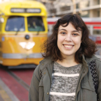 woman poses with train in background