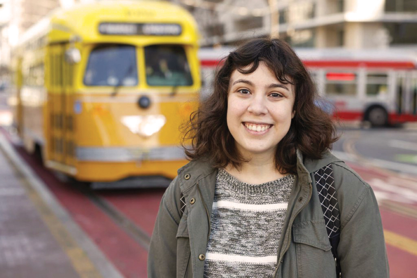 woman poses with train in background