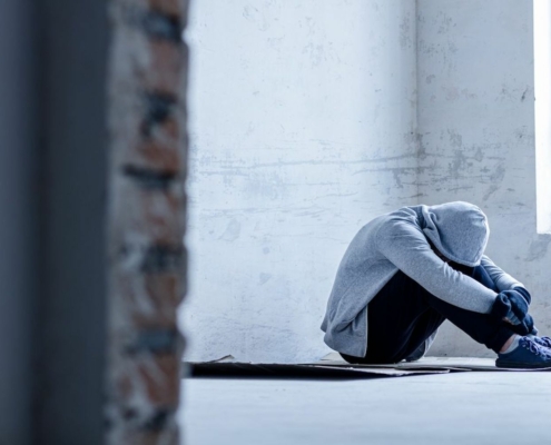 young man in gray hooded seated and bent over