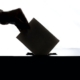silhouette of hand placing ballot into box
