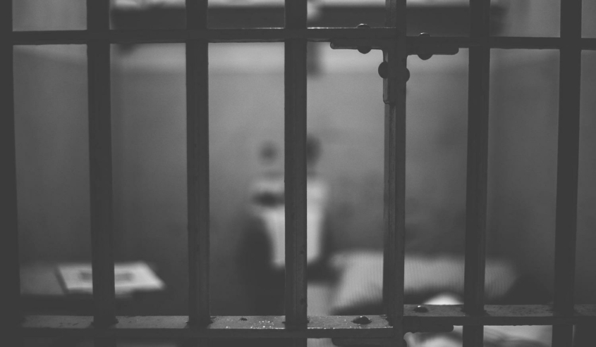black and white shot of prison cell behind bars