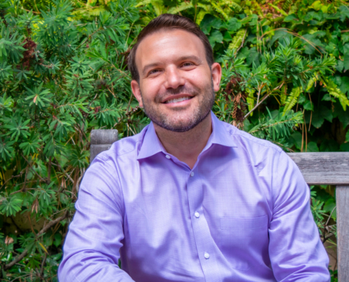 man in purple shirt sitting on outdoor bench
