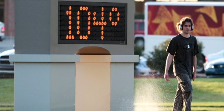 Man walking next to thermometer reading 104 degrees