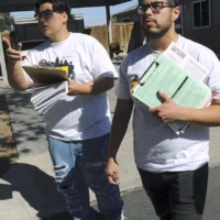 Two young men with clipboards canvassing neighborhood