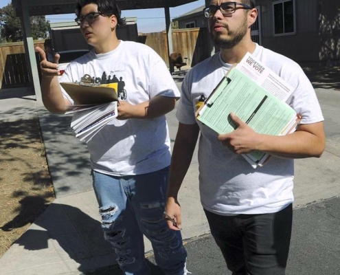 Two young men with clipboards canvassing neighborhood