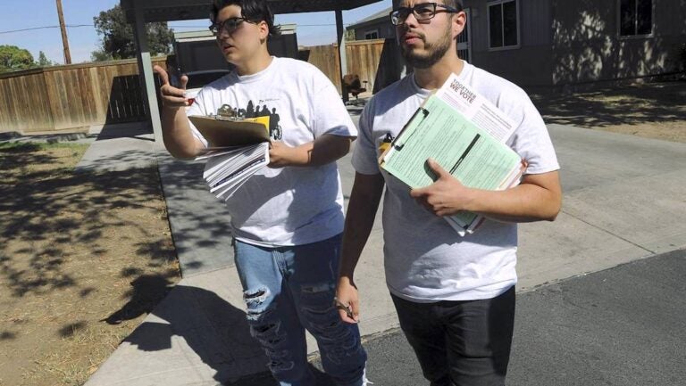 Two young men with clipboards canvassing neighborhood